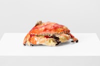 a sculpture of a crab sitting on a white surface